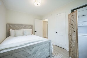 A bedroom with a bed, a wardrobe, and a door leading to another room. - Serene 3BR Retreat, walk to URMC, RIT & Golisano (Rochester)
