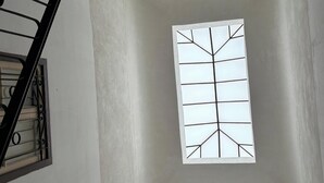 Um lance de escadas com janela geométrica e corrimão de metal.