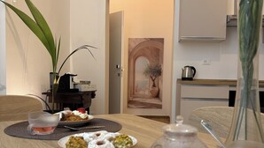 Uma mesa de jantar com pratos de comida, um vaso com uma planta e uma pintura de um arco.