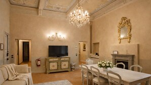 A dining room with a chandelier, a television, a fireplace, and a mirror. - Avignonesi - Chic Frescoed Palace - 2BR 2BA - Heart of Montepulciano (Montepulciano)
