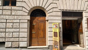 A stone building with a wooden double door, a signboard, and a window. - Avignonesi - Chic Frescoed Palace - 2BR 2BA - Heart of Montepulciano (Montepulciano)