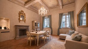 A spacious room with a dining table, chairs, a fireplace, a sofa, and a chandelier. - Avignonesi - Chic Frescoed Palace - 2BR 2BA - Heart of Montepulciano (Montepulciano)