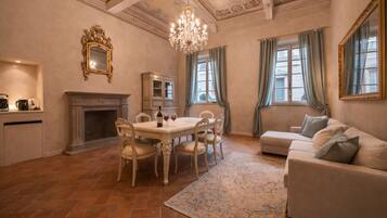 Une pièce spacieuse comprenant une table à manger, des chaises, une cheminée, un canapé et un lustre.