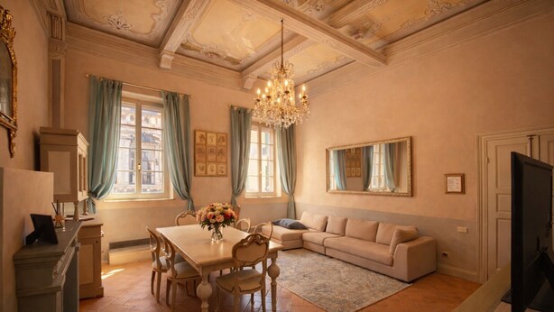 A spacious living room with a dining area, a chandelier, and a television. - Avignonesi - Chic Frescoed Palace - 2BR 2BA - Heart of Montepulciano (Montepulciano)
