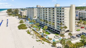 Ett hotell med flera våningar, balkonger, utsikt över stranden och en parkeringsplats.