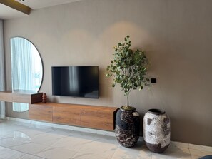 Ein modernes Wohnzimmer mit einem flachbildfernseher an der Wand, einer Holzkonsole darunter und zwei großen Vasen auf dem Boden.