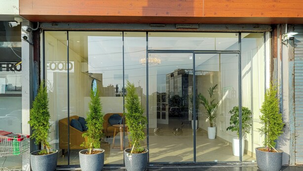 A modern building with a glass entrance, potted plants, and a seating area inside. - Hotel Tranquil Airport Road Sector 66 Mohali Chandigarh (Mohali)