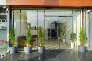 A modern building with a glass entrance, potted plants, and a seating area inside. - Hotel Tranquil Airport Road Mohali Chandigarh (Mohali)