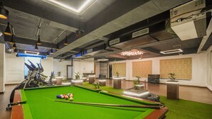 A billiards room with a pool table, exercise bikes, and potted plants. - Hotel Escala - Near Golden Gate Amritsar (Amritsar)