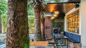 An outdoor seating area with tables and benches, surrounded by greenery and trees. - Hotel Escala - Near Golden Gate Amritsar (Amritsar)