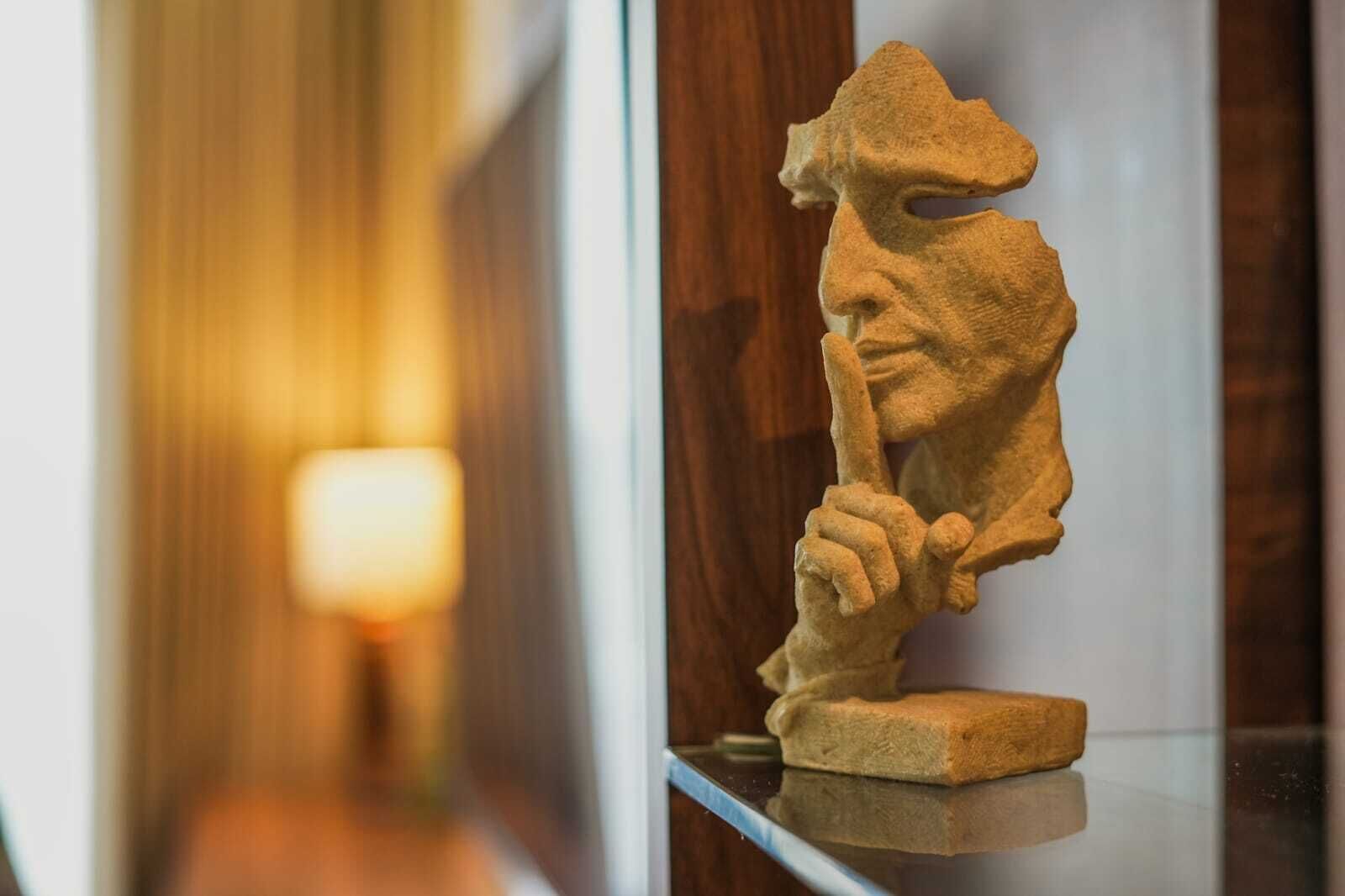 Escultura de una figura sosteniendo un báculo, exhibida en una vitrina.