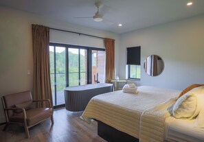 A bedroom with a bed, a chair, a table, a ceiling fan, and a window with curtains.