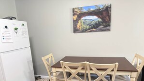 A dining area with a table and chairs, a refrigerator, and a framed landscape picture on the wall. - The Lazy Hiker I Cozy 2BR I 15m to RRG I Wi-Fi (Stanton)