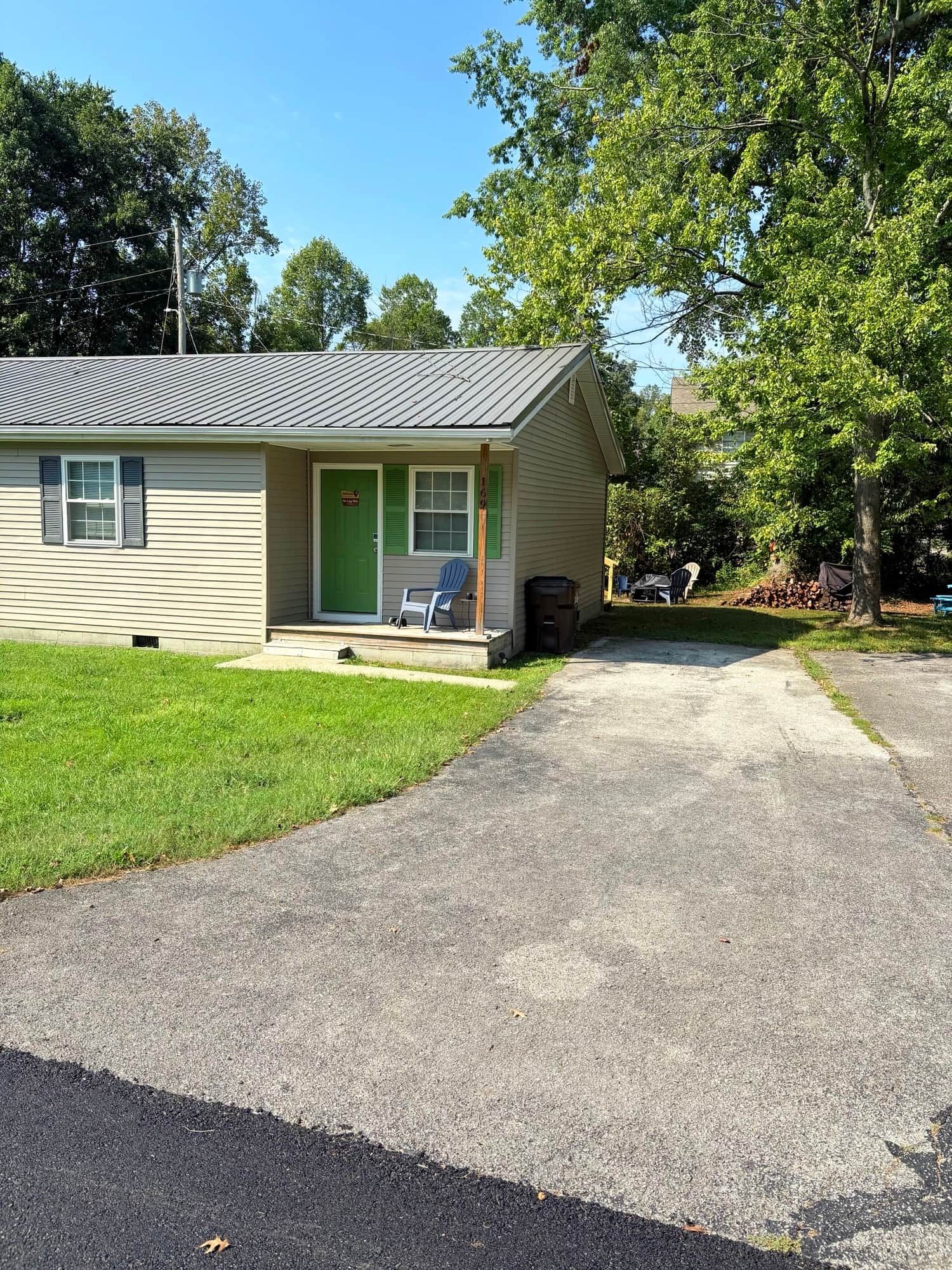 A single-story house with a front porch, a green door, and a small lawn.