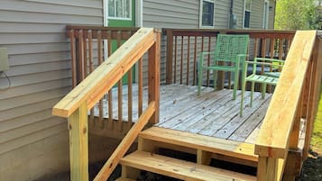 Une terrasse en bois avec une rampe menant à une porte verte, le tout entouré d’une clôture.