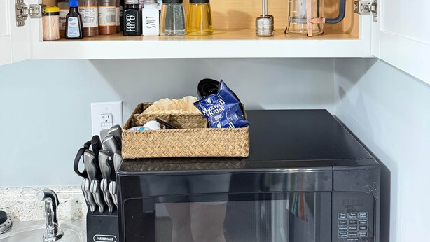 A kitchen with a microwave, a coffee maker, and a cabinet containing various kitchen items. - The Lazy Hiker I Cozy 2BR I 15m to RRG I Wi-Fi (Stanton)