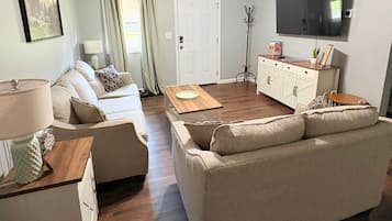 A living room with a sofa, a coffee table, a television, and a door.