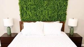 A bed with a white duvet, a green wall-mounted plant, and two nightstands with lamps. - The Lazy Hiker I Cozy 2BR I 15m to RRG I Wi-Fi (Stanton)