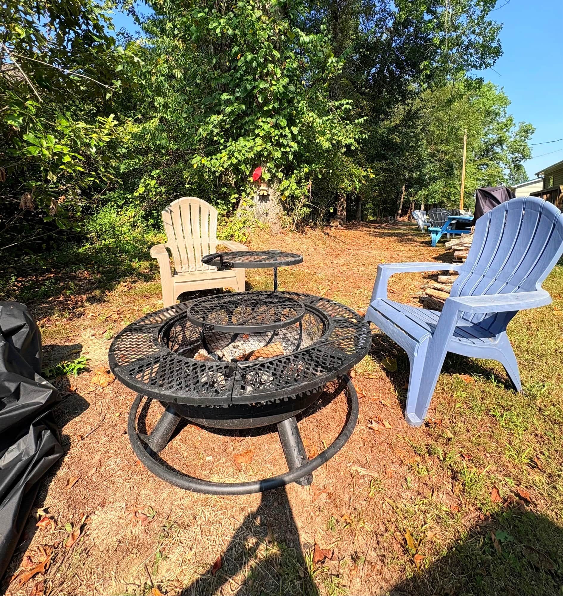 Un espace extérieur aménagé avec un foyer, deux fauteuils Adirondack et une table.