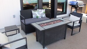 Un patio exterior con sofá, sillas, una mesa y una parrilla.