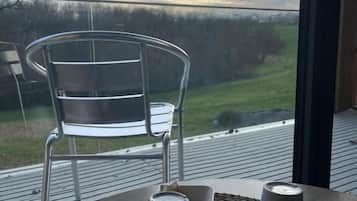 Une table avec deux tasses et sous-tasses blanches, un set de table en fibres tressées et une chaise avec un cadre en métal.