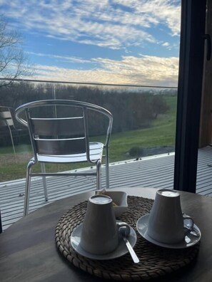 Une table avec deux tasses et sous-tasses blanches, un set de table en fibres tressées et une chaise avec un cadre en métal.