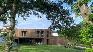 A modern two-story building with a flat roof, large windows, and a covered outdoor seating area. - Les libellules (Gémil)