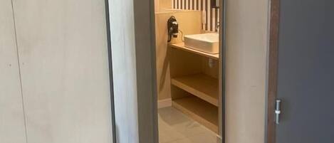A mirror reflecting a bathroom with a sink and vertical stripes on the wall.