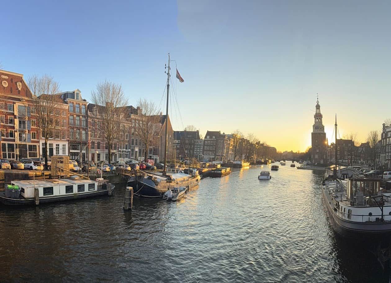 Un canal bordé de bateaux et de bâtiments, avec une tour en arrière-plan.
