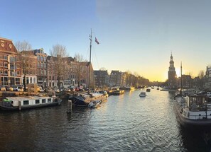 A canal with boats, buildings, and a tower in the background.
