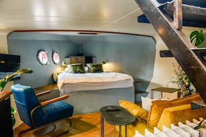 Een compacte, moderne slaapkamer met een bed, zithoek en een klein tafeltje.