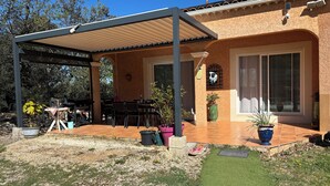 A covered patio with a table and chairs, a grill, and potted plants. - Villa with swimming pool in the Cévennes 10 people electric charging point (Mons)