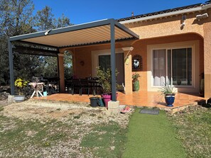 A covered patio with a table and chairs, a grill, and potted plants. - Villa with swimming pool in the Cévennes 10 people electric charging point (Mons)