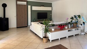 A modern living room with a sofa, TV, and potted plants. - Villa with swimming pool in the Cévennes 10 people electric charging point (Mons)
