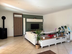 A modern living room with a sofa, TV, and potted plants. - Villa with swimming pool in the Cévennes 10 people electric charging point (Mons)