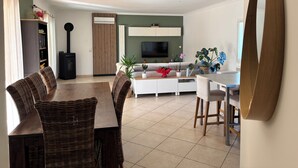 A modern living room with a dining area, a fireplace, a TV, and a large mirror. - Villa with swimming pool in the Cévennes 10 people electric charging point (Mons)