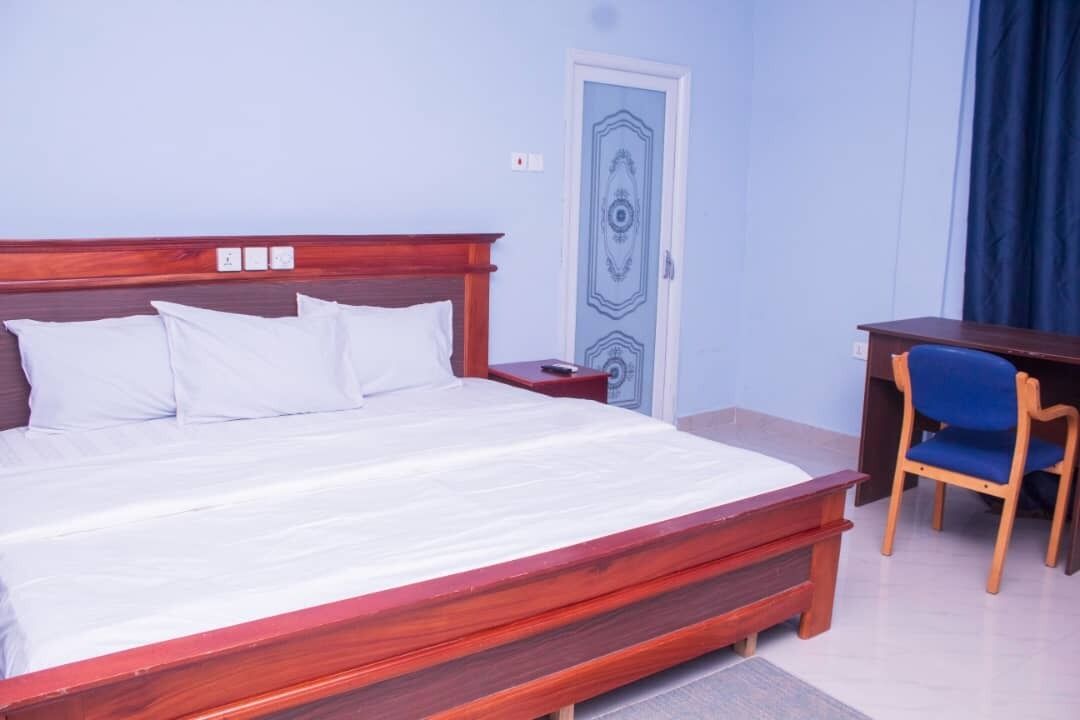 A bedroom with a wooden bed, a desk, and a chair.