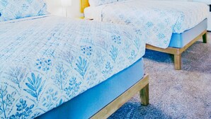 Une chambre avec deux lits, un plafond en bois, des murs blancs et une fenêtre.