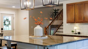 A kitchen with a marble island, wooden cabinets, and a vase with orange flowers. - Wonderful 4-bedroom house with AC in charming Lafayette (Lafayette)