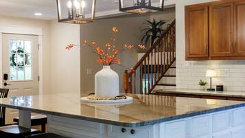 A kitchen with a marble island, wooden cabinets, and a vase with orange flowers.