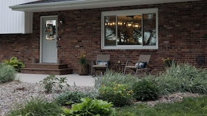 A brick house with a front porch, a door with a wreath, two wicker chairs, and a window with lights. - Wonderful 4-bedroom house with AC in charming Lafayette (Lafayette)
