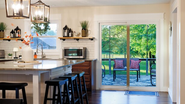 A kitchen with a large island, bar stools, a microwave, and a view of a patio with outdoor seating. - Wonderful 4-bedroom house with AC in charming Lafayette (Lafayette)