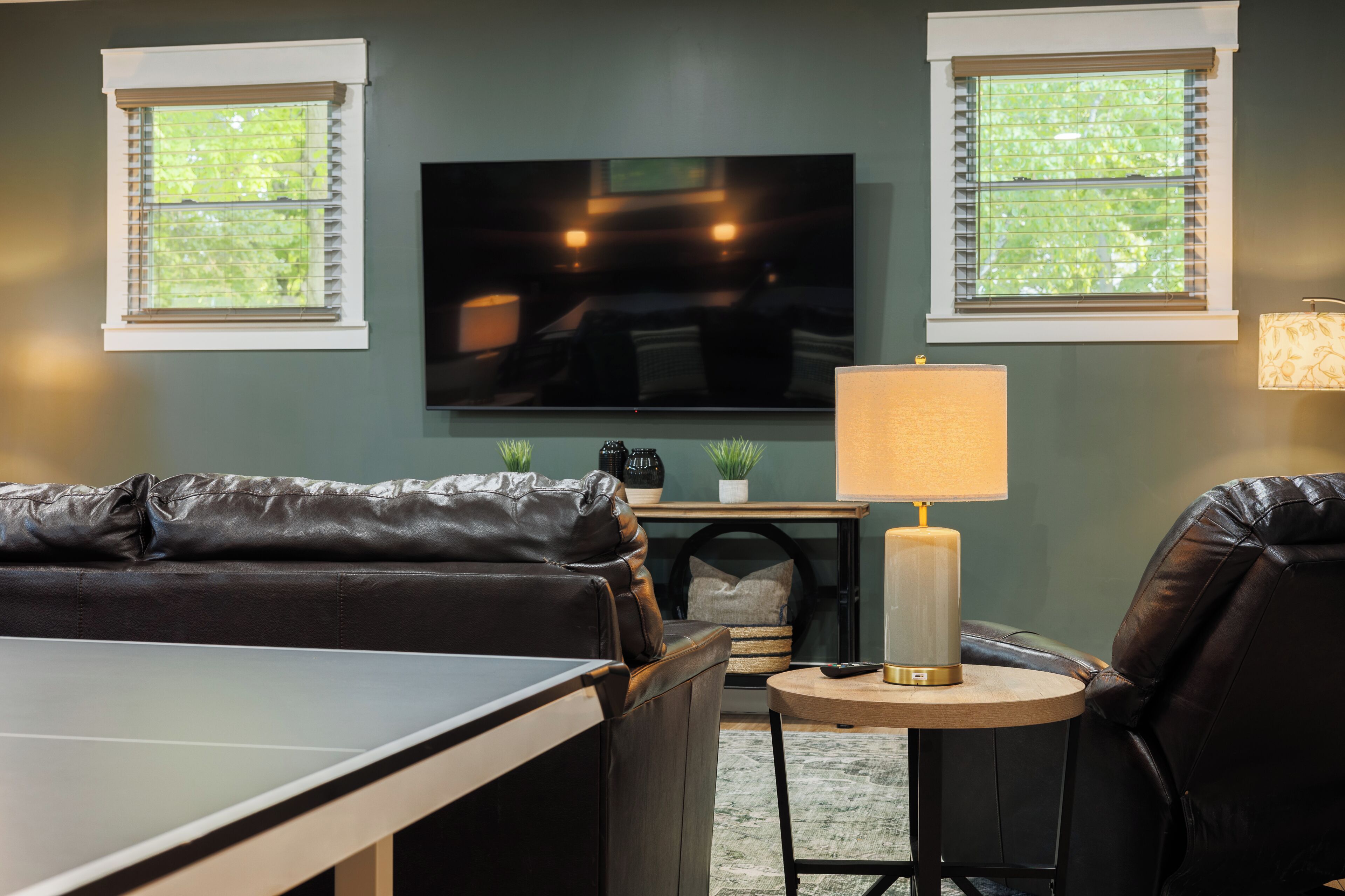 A living room with a TV, a sofa, a small table, and a lamp.