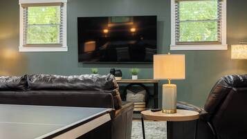 A living room with a TV, a sofa, a small table, and a lamp.