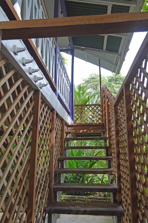 A wooden staircase with a lattice railing, leading to a covered area with a view of lush greenery. - Villa on the Caribbean Coast (Puerto Viejo de Talamanca)