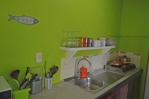 A kitchen with green walls, a fish decoration, a sink, a dish rack, and various utensils. - Villa on the Caribbean Coast (Puerto Viejo de Talamanca)