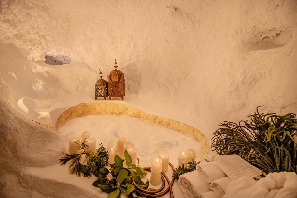 Un bain de glace agrémenté de bougies, une petite structure en bois et de la verdure.