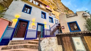 Un edificio con una escalera que conduce a una puerta, un balcón y vistas a un acantilado.