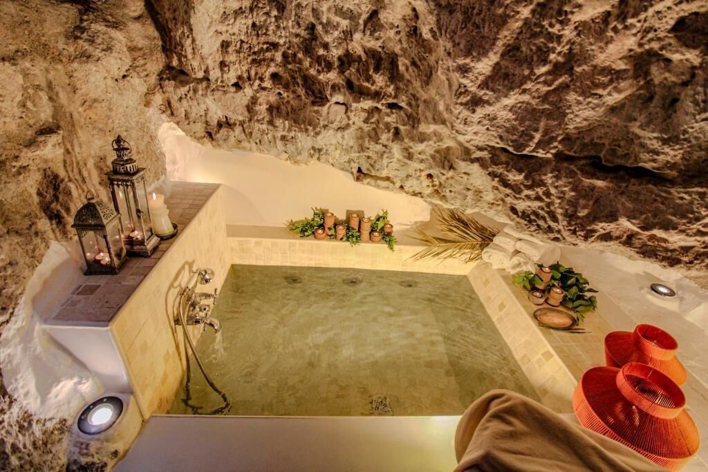 Un área de spa con una bañera grande, plantas decorativas y un farol.