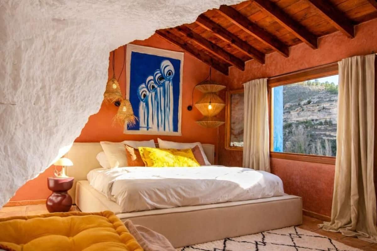 Un dormitorio con cama, un cuadro, una ventana con cortinas y vistas al exterior.